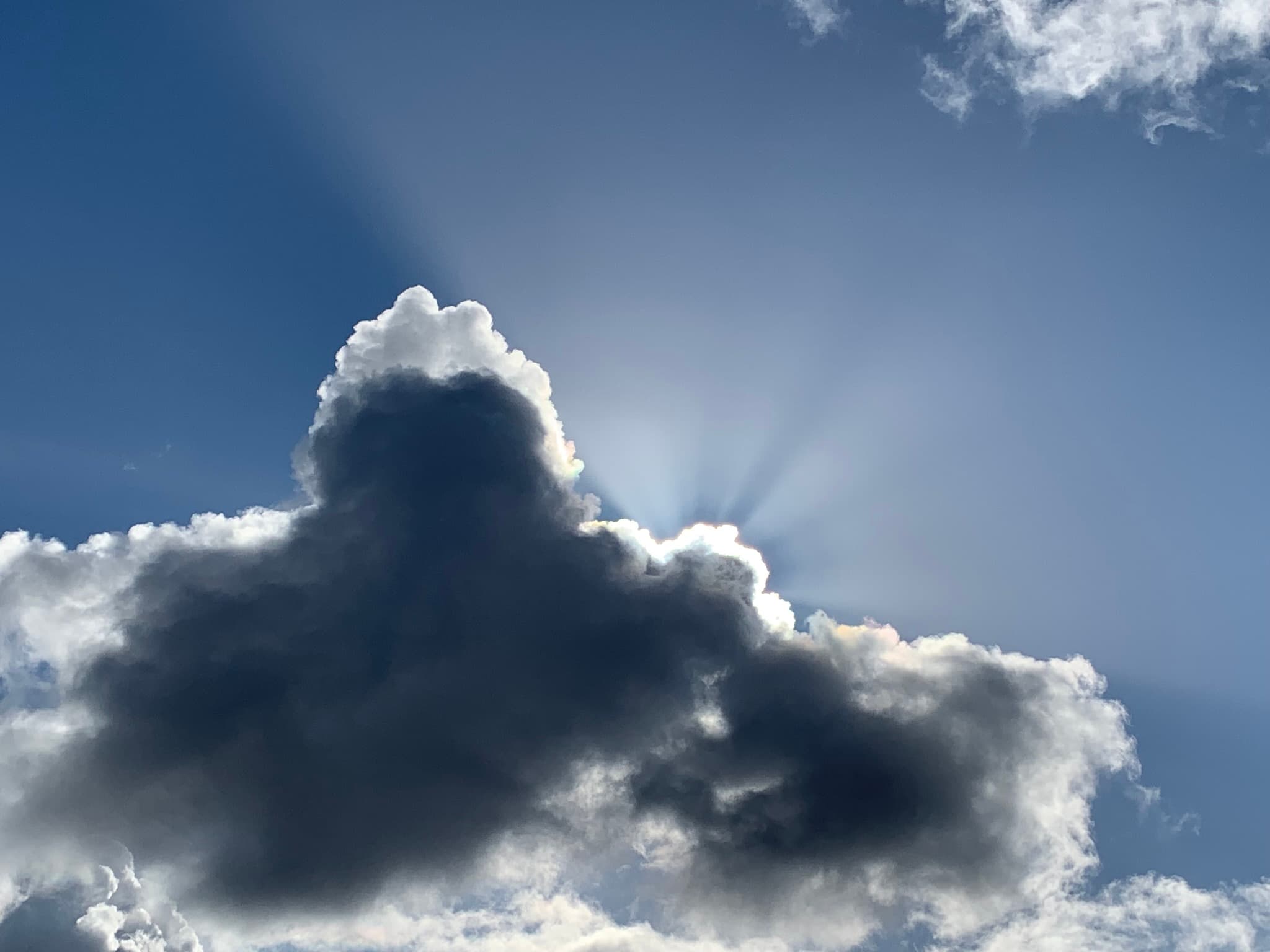Sunrays breaking from behind a Pacific Northwest storm cloud — weathered but hopeful