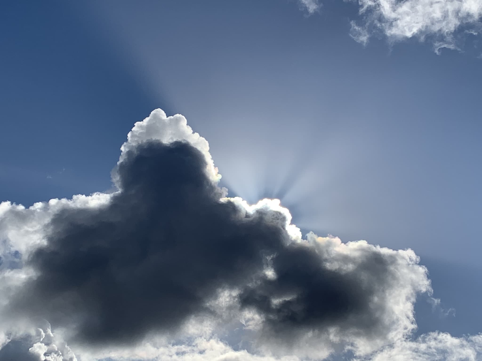 Sunrays breaking from behind a Pacific Northwest storm cloud, weathered but hopeful